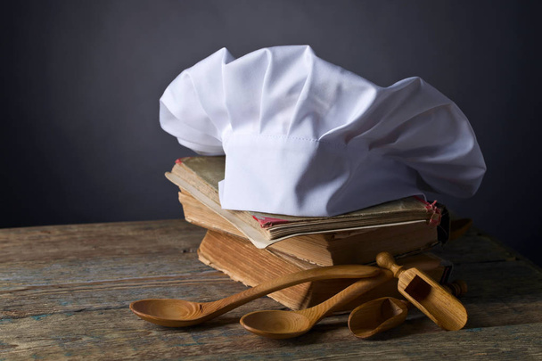 Eski mutfak kitaplar, aşçı şapkası ve tahta kaşıklar . - Fotoğraf, Görsel