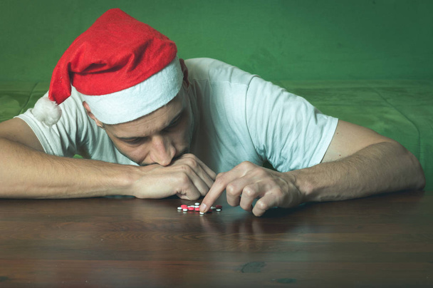 Young man with Santa Claus hat suffering from suicidal depression feeling lonely and sad for New Year and Christmas holiday suicide concept - Φωτογραφία, εικόνα
