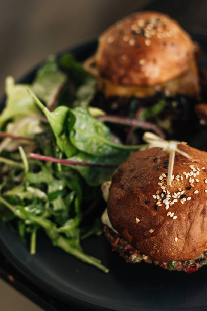 finom hamburgert a fekete nyomólapra kávézóban saláta - Fotó, kép
