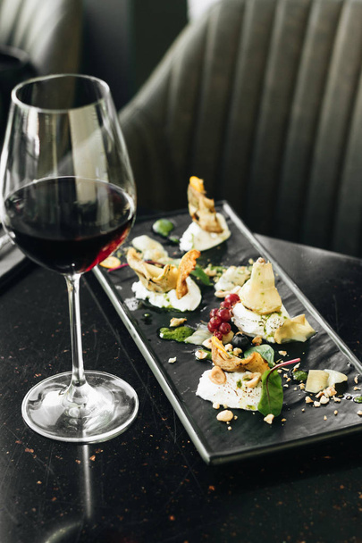 wijnglas met rode wijn en antipasti instellen op tabel in café  - Foto, afbeelding
