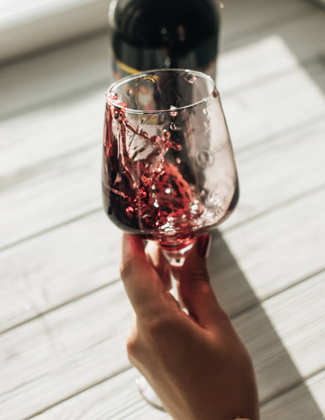 женская рука держит бокал с красным вином на столе в кафе
  - Фото, изображение