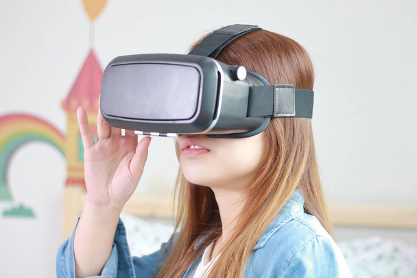 Jeune femme portant des lunettes de réalité virtuelle à la maison
. - Photo, image
