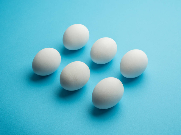 White chicken eggs on the blue background. - Φωτογραφία, εικόνα