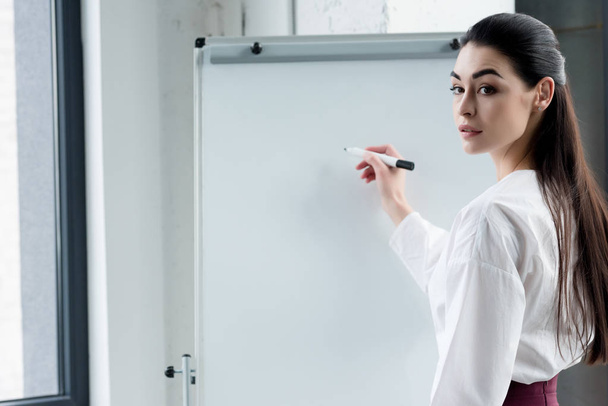 beautiful young businesswoman writing on blank whiteboard in office - Photo, image
