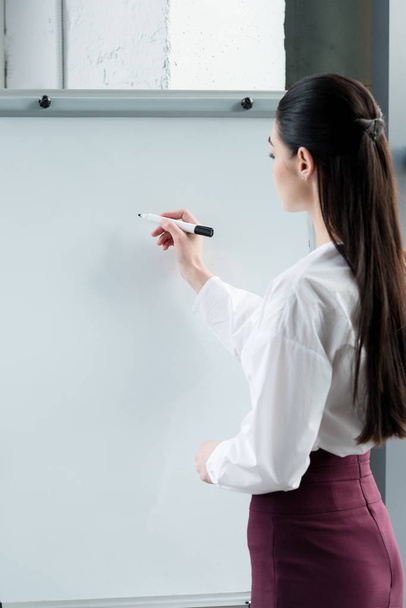 side view of young businesswoman writing on blank whiteboard - Photo, Image