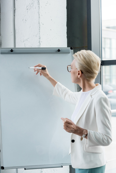 mulher de negócios profissional em óculos escrevendo no quadro branco no escritório
 - Foto, Imagem