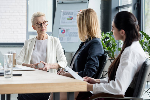 боковой вид красивых деловых женщин, говорящих на встрече в офисе
 - Фото, изображение