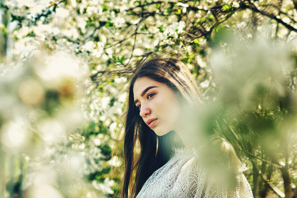 Portrait of a young girl in a flowering Park . Stylish girl at cherry blossom - Foto, imagen