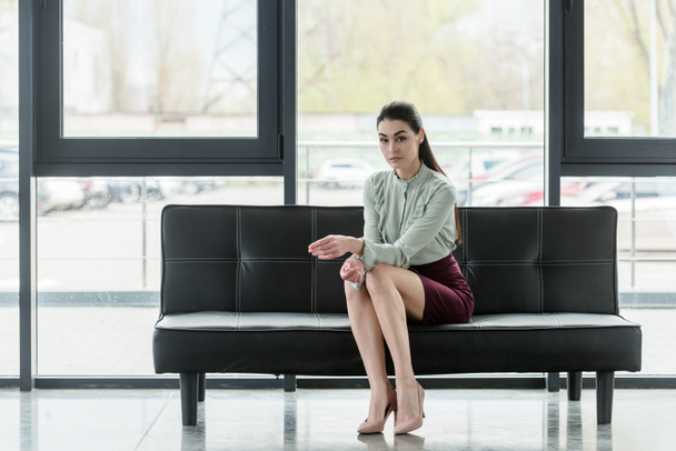 attractive businesswoman sitting on sofa in office - Foto, afbeelding