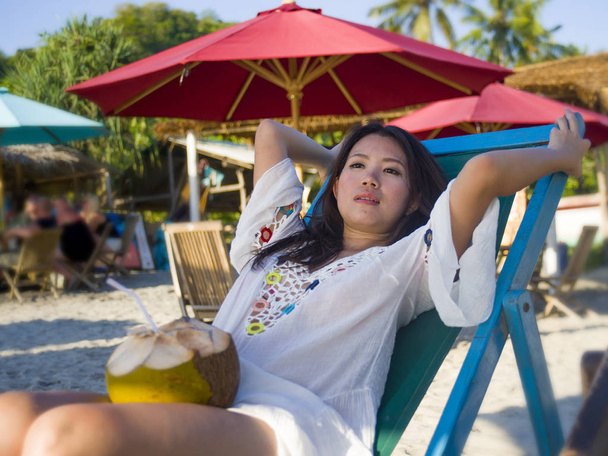 young beautiful and happy Asian Korean or Chinese woman 20s drinking relaxed coconut juice on tropical paradise beach resort in summer holidays  - Fotoğraf, Görsel