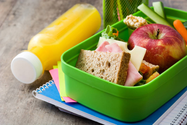 Pranzo scolastico sano: sandwich, verdure, frutta e succo di frutta sul tavolo di legno
.  - Foto, immagini