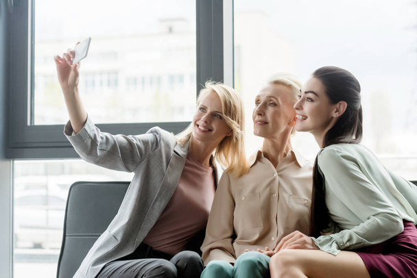 belle imprenditrici scattare selfie con smartphone in ufficio
 - Foto, immagini