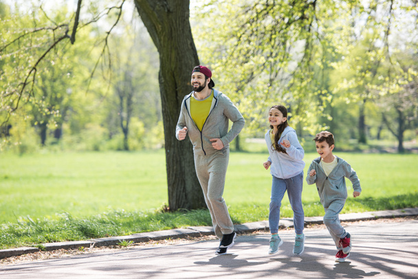 onnellinen urheilullinen perhe kulkee polulla puistossa
  - Valokuva, kuva