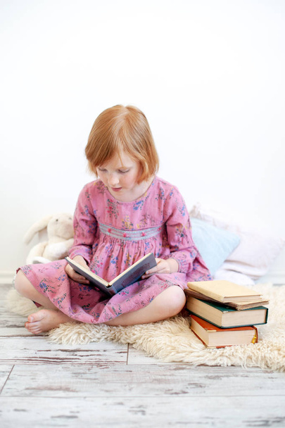 A girl in a dress is reading a book - Фото, зображення