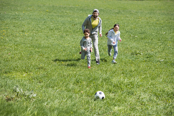 happy sportive family playing football on grassy meadow  - Foto, Imagem