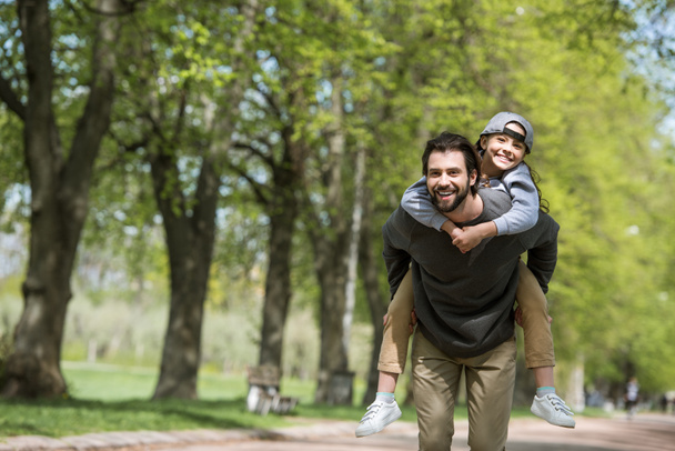 happy father doing piggyback ride to daughter in park  - Fotografie, Obrázek