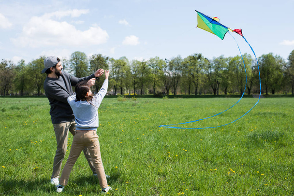 smiling father and daughter flying kite on meadow in park - Valokuva, kuva
