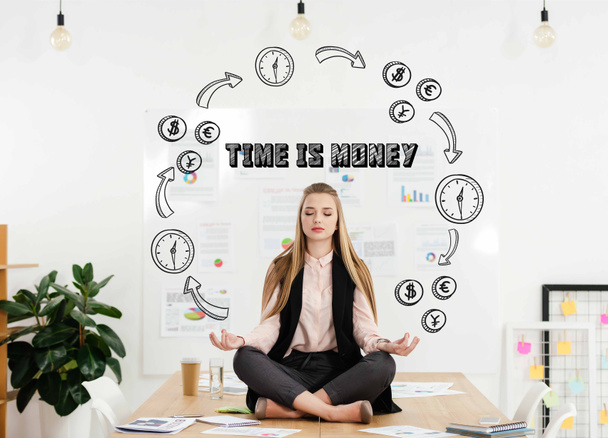 nyugodt üzletasszony meditál a lótusz helyzet asztalra hivatalban-val alkalommal felirat pénzt és időt és pénzt áramkör - Fotó, kép