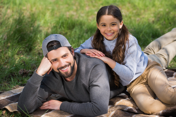 Glückliche Tochter und Vater liegen auf Plaid im Park - Foto, Bild