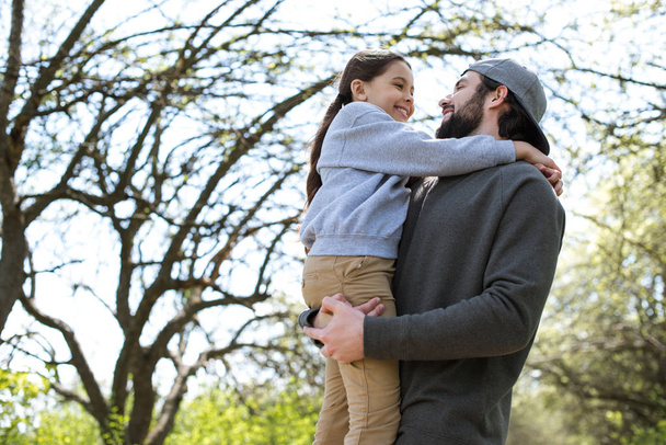 low angle view of father holding daughter in park - Photo, Image