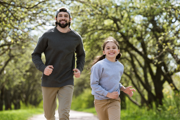 улыбающиеся отец и дочь бегут в парке
  - Фото, изображение