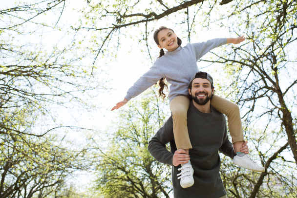 vista de ángulo bajo de la hija sentada en los hombros del padre en el parque
 - Foto, Imagen