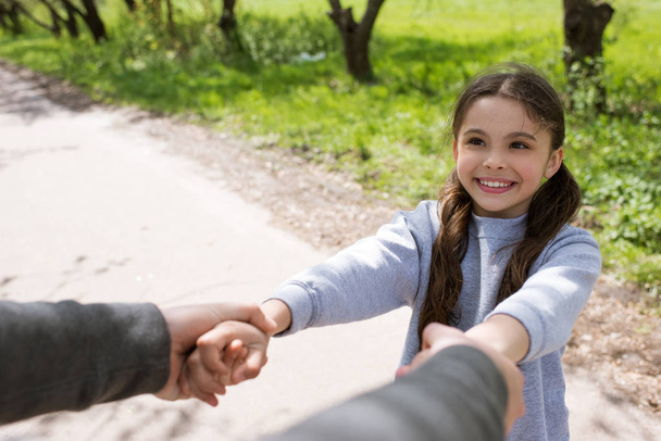 cropped image of man holding smiling daughter hands in park - Foto, immagini