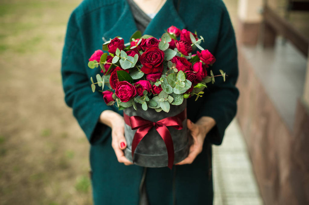το κορίτσι κρατά στα χέρια της ένα μπουκέτο από κόκκινα τριαντάφυλλα - Φωτογραφία, εικόνα