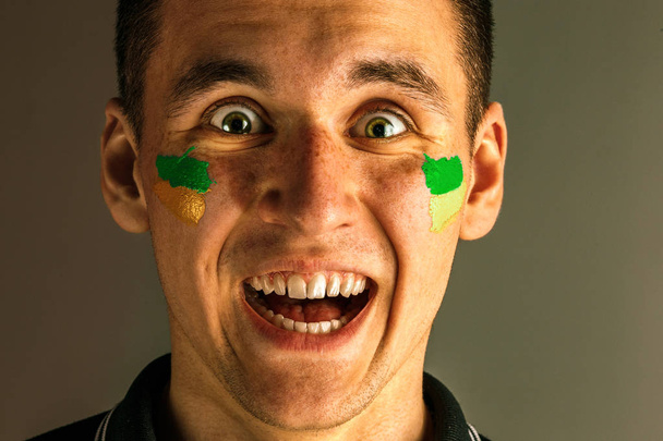 Portrait of a man with the flag of the Brazil painted on him face. - Zdjęcie, obraz
