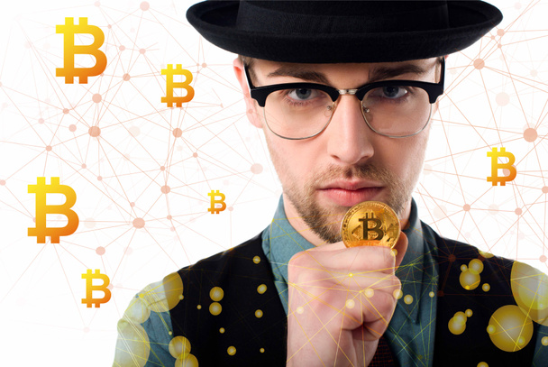 Portrait of man in eyeglasses and hat holding golden bitcoin on white - Foto, immagini