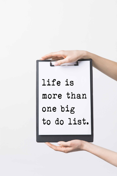 partial view of woman holding clipboard with "Life is more then one big to do list" inspiration in hands, isolated on white  - Photo, Image