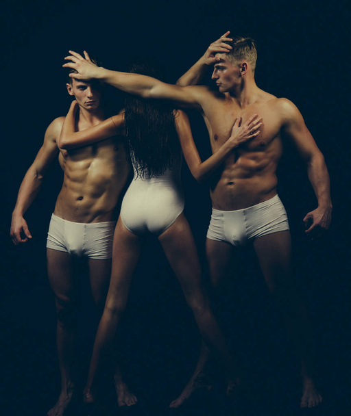 Twins men with muscular body and girl coach. Gymnastic school and energy. Circus gymnasts at pilates or yoga training. Fitness and dieting. Flexibility in acrobatics. Sport people or team work - Fotó, kép