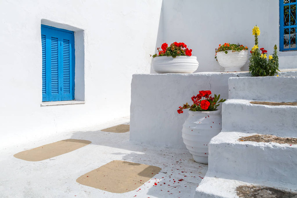 Casa tradicional griega azul y blanca con flores en macetas grandes
 - Foto, Imagen