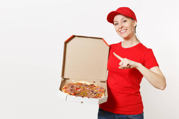 Delivery woman in red uniform isolated on white background. Pretty female in cap, t-shirt, jeans working as courier or dealer holding italian pizza in cardboard flatbox. Copy space for advertisement. - Photo, Image