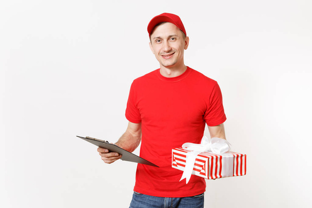 Delivery man in red uniform isolated on white background. Male courier or dealer, holding pen, clipboard with papers document, with blank empty sheet, ed striped gift box with present. Copy space. - Photo, Image