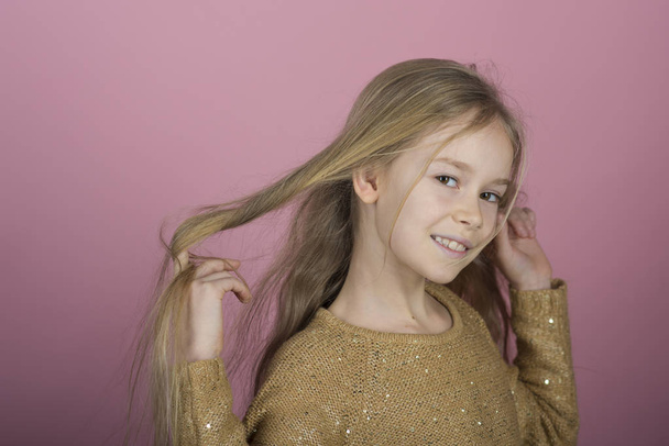 Pretty joyful young girl with long hair on pink background. Lovely sweet moments of little princess, pretty friendly child having fun to camera - Photo, image