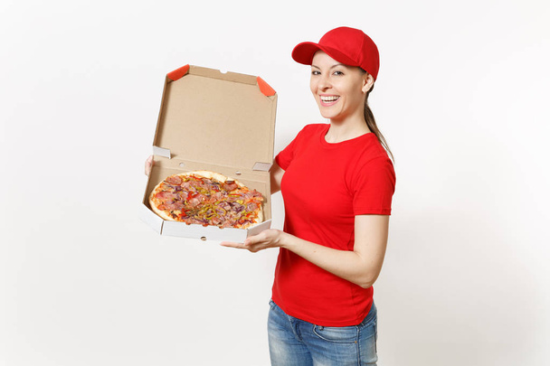 Livraison femme en uniforme rouge isolé sur fond blanc. Jolie femme en bonnet, t-shirt, jeans travaillant comme coursier ou revendeur tenant une pizza italienne dans une boîte à plat en carton. Espace de copie pour la publicité
. - Photo, image