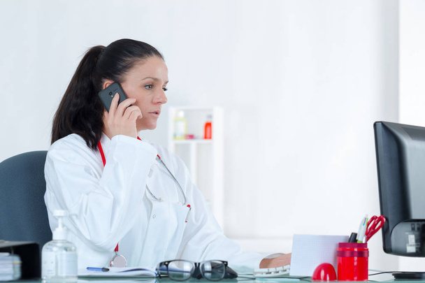 portrait of cheerful young female doctor on phone at office - Foto, imagen