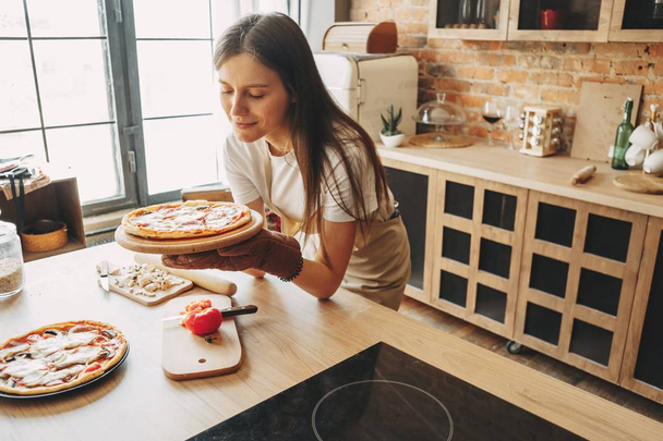 Young woman housewife baking pizza for her family - 写真・画像