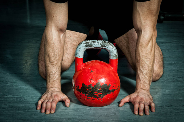 Strong muscular man with big muscles preparing for heavy kettle bell training and workout in the gym - Fotoğraf, Görsel
