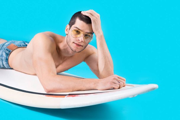 Привлекательный серфер лежит на доске
 - Фото, изображение