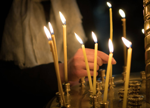 Woman lights the candle in russian orthodox church. Close-up. - Photo, Image