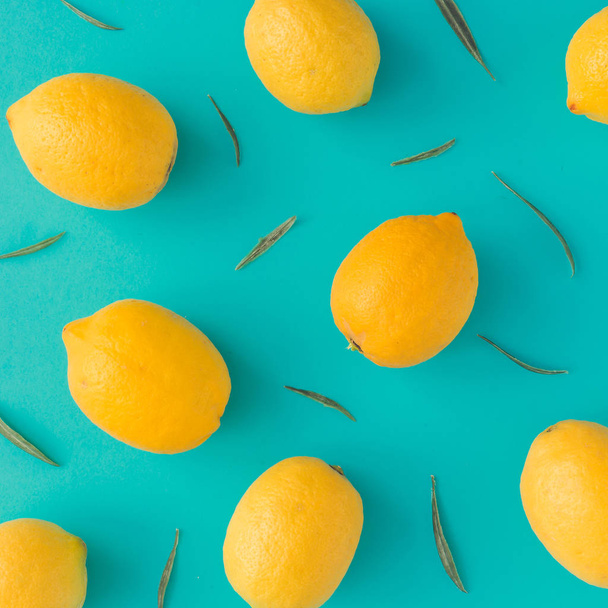 Creative summer pattern made of lemons and green leaves on bright blue background. Fruit minimal concept. - Foto, afbeelding