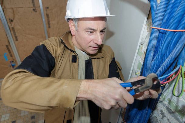 elektricien snijden kabels in een bouwplaats - Foto, afbeelding