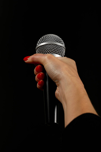Vrouw hand met microfoon geïsoleerd op zwart - Foto, afbeelding
