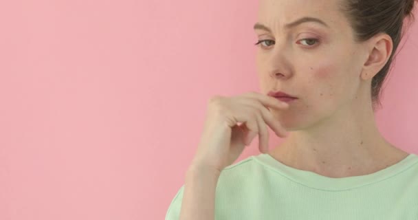 Pretty girl shows indignation pink background - Footage, Video