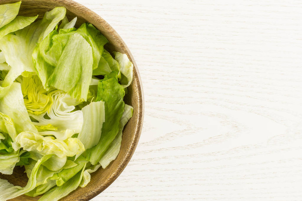 Iceberg lettuce fresh torn salad leaves in a wooden bowl table top isolated on grey wood backgroun - 写真・画像