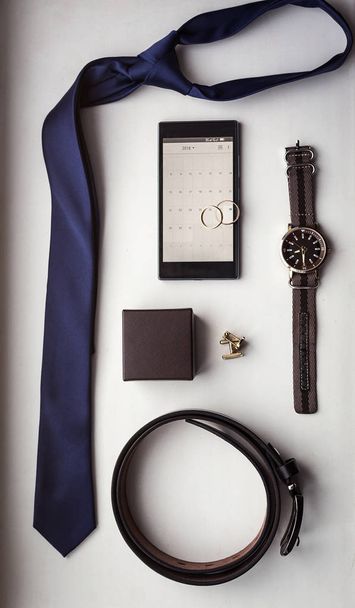 Different men's accessories such as: cufflinks, watches,  rings, belt, tie and phone - are on the table - Foto, Imagem