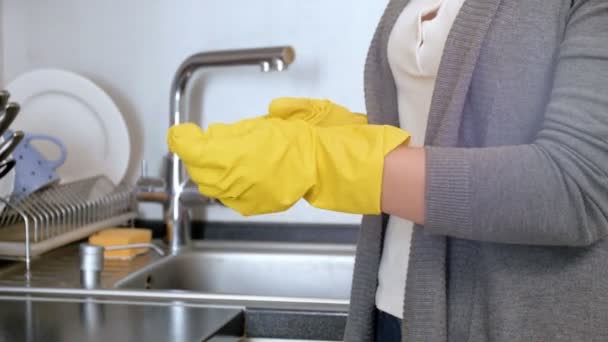 Nahaufnahme 4k Filmmaterial der jungen Hausfrau, die gelbe Latex-Handschuhe auszieht, nachdem sie Hausarbeit in der Küche erledigt hat - Filmmaterial, Video