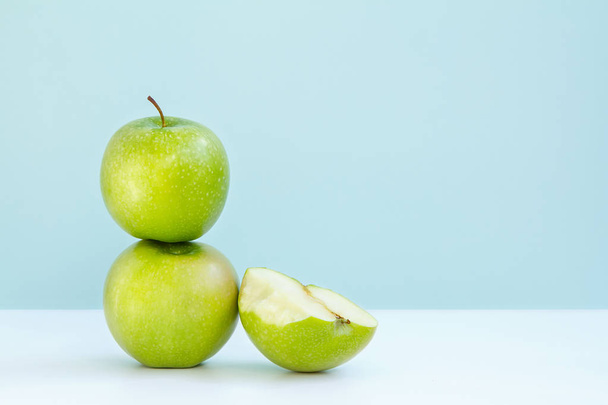 ein grüner Apfel auf einen anderen und ein halb gebissener Apfel auf blauem Hintergrund - Foto, Bild